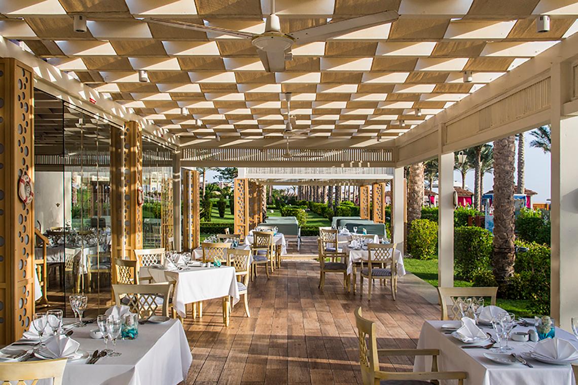 Restaurantterrasse des Rixos Sharm El Sheikh mit gedeckten Tischen und Deckenventilatoren
