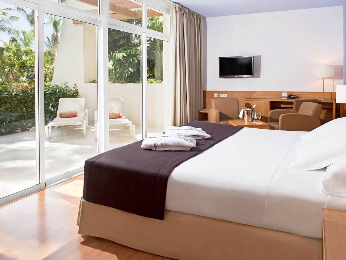 Ein modernes Hotelzimmer mit Doppelbett, Balkonzugang und Gartenblick im Tabaiba Princess Hotel.