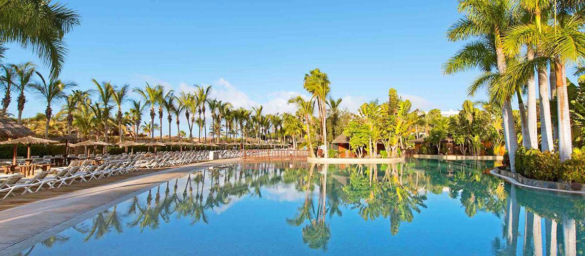 Ein großer Swimmingpool im Tabaiba Princess Hotel, umgeben von Palmen und Liegestühlen.