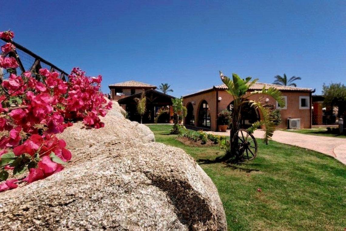 Außenansicht des Alma Resorts mit Gebäuden, Blumen und Rasen