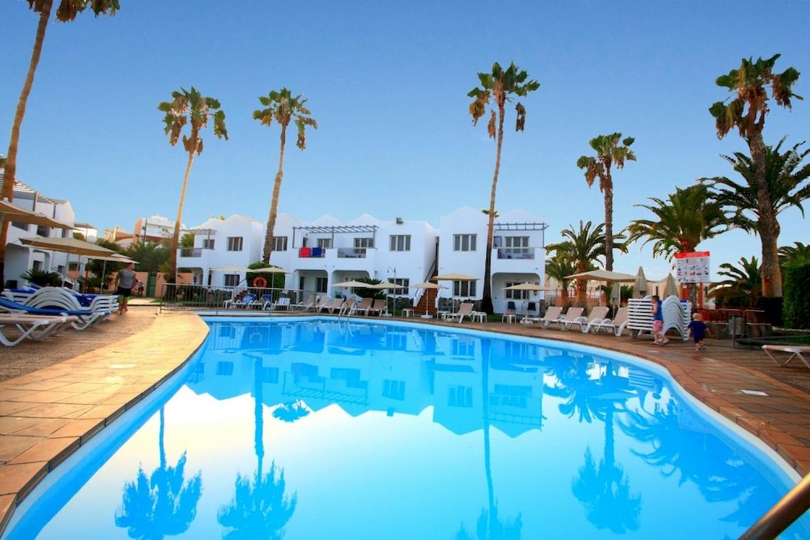 Pool des Turbo Club Hotels mit weißen Gebäuden und Palmen im Hintergrund.