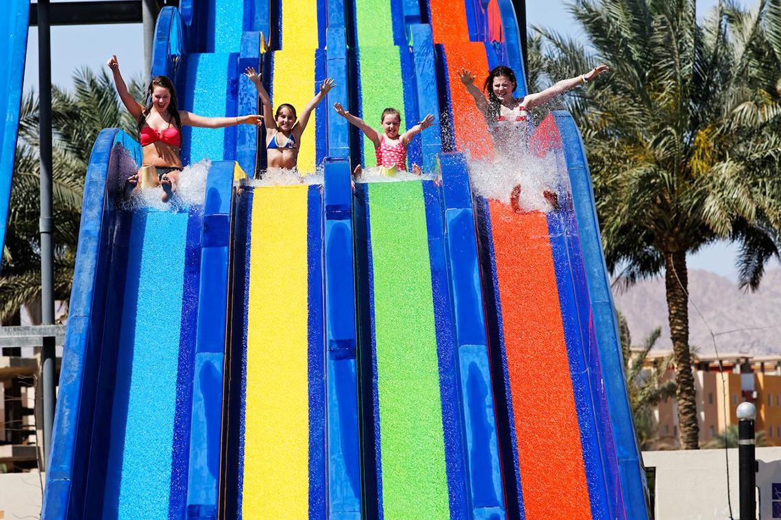 Vier Maedchen rutschen auf einer regenbogenfarbenen Wasserrutsche im Pickalbatros Royal Moderna Resort
