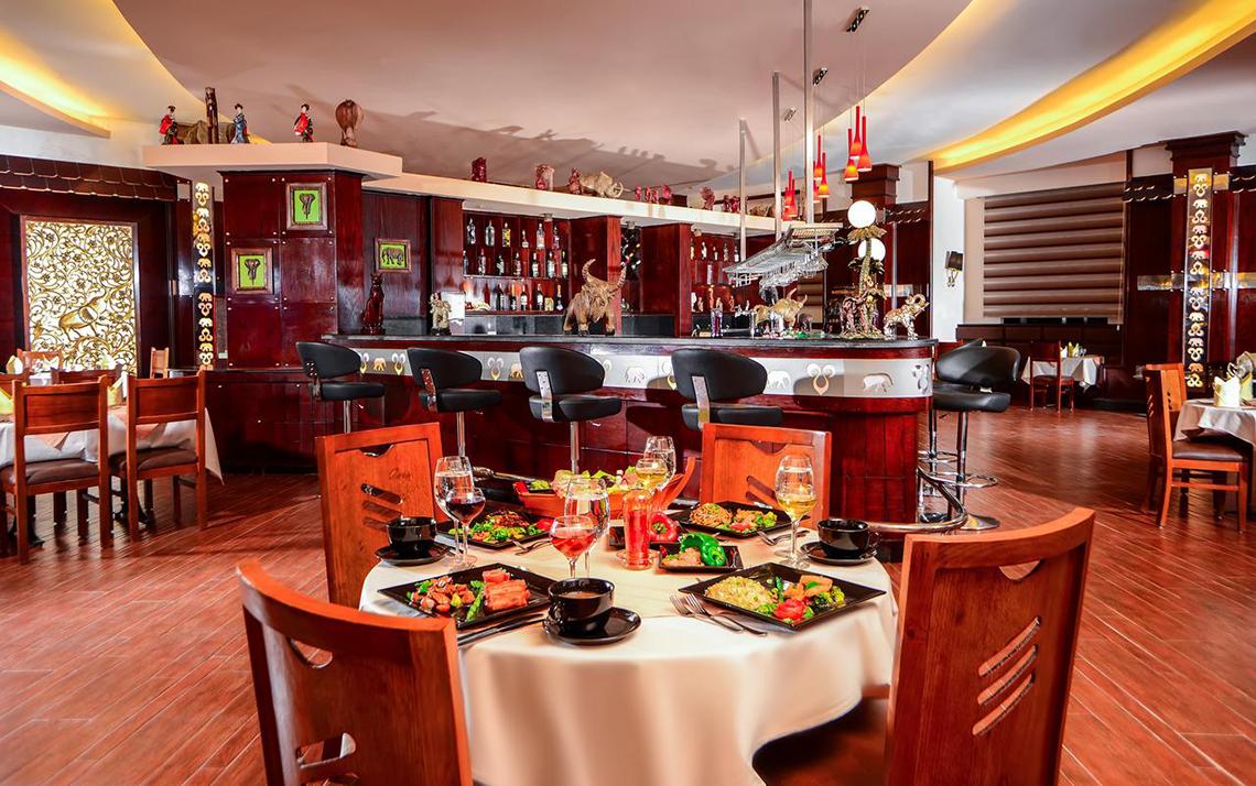 Innenansicht des Restaurants im Pickalbatros Royal Moderna Resort mit voll besetztem Tisch und Bar im Hintergrund.