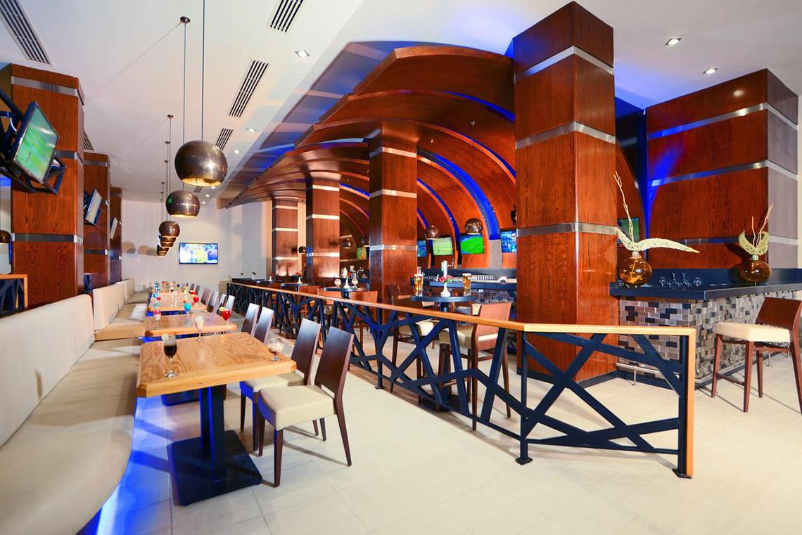 Restaurantbereich des Pickalbatros Royal Moderna Resorts mit Holzmöbeln, Tischen, Stühlen und Fernsehern.