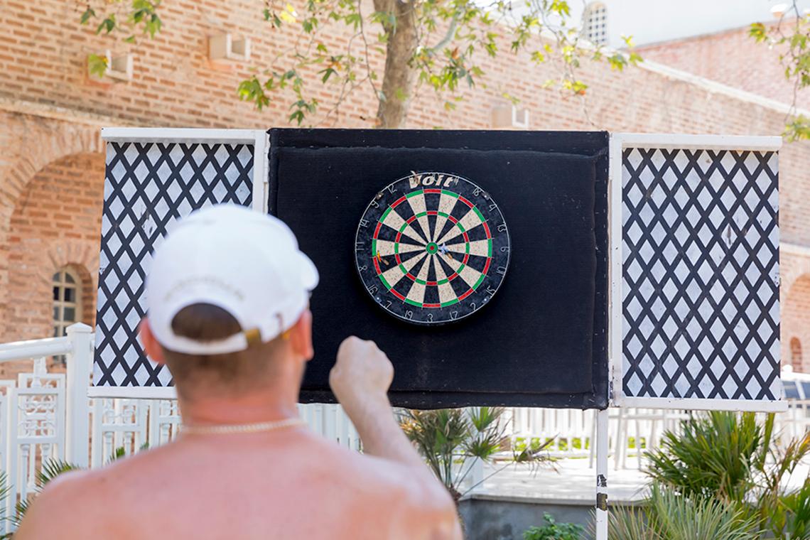 Ein Mann wirft einen Dart auf eine Dartscheibe vor dem Swandor Hotels & Resorts Topkapi Palace.