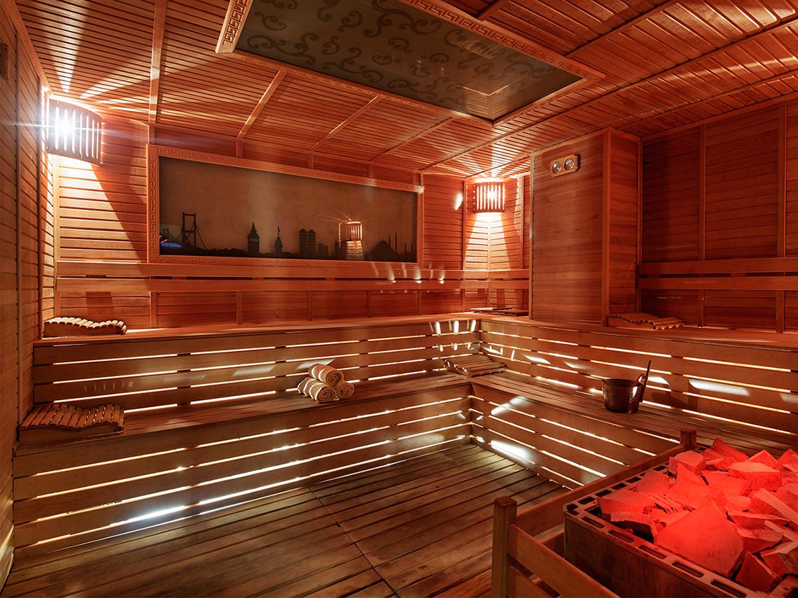 Innenansicht der Sauna im Kristall Waterworld Aqua Collection Hotel mit Holzwänden und Decken, Sitzbänken und einem Bild an der Wand.