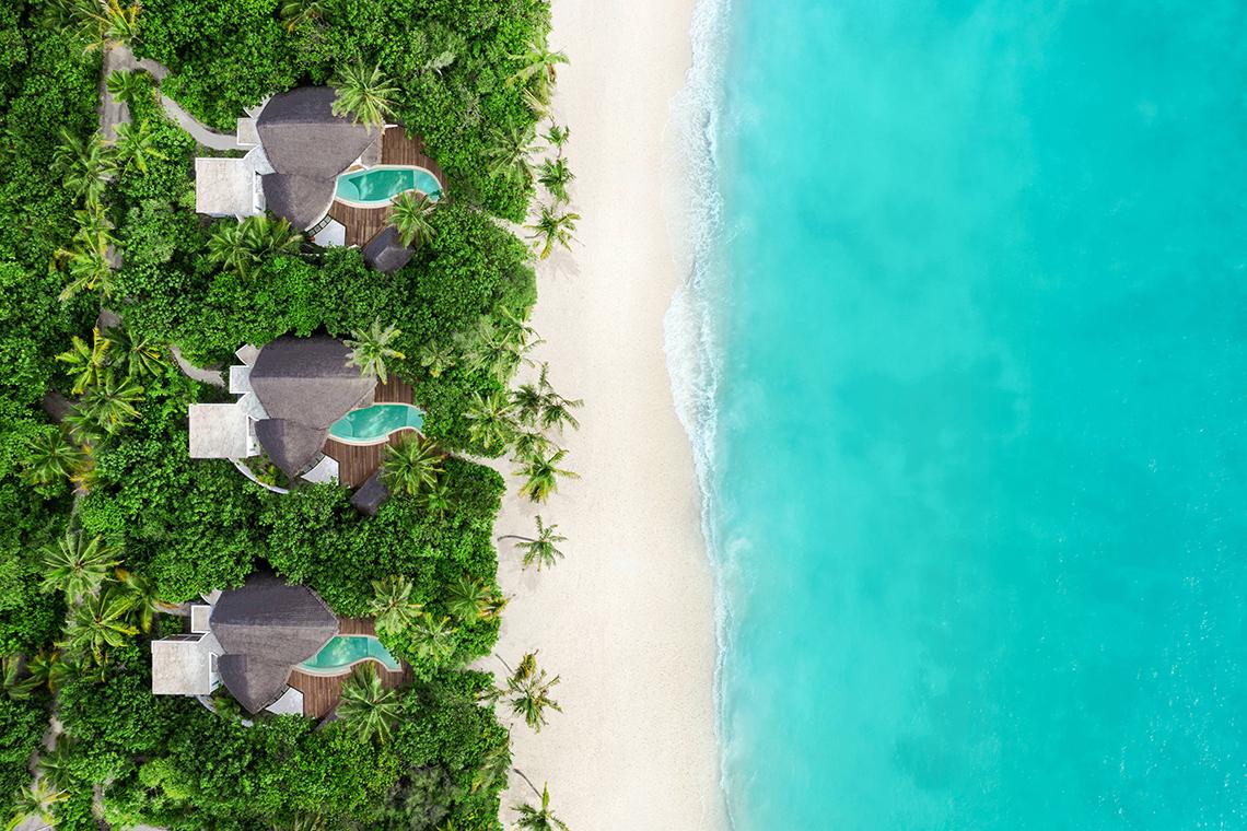 Luftaufnahme des JW Marriott Maldives Resort & Spa mit drei runden Gebäuden am Strand und Infinity-Pools.