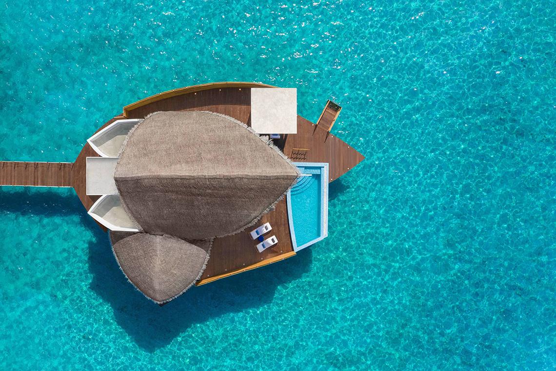 Luftaufnahme der Überwasser-Villa im JW Marriott Maldives Resort & Spa mit Pool und Sonnenliegen.