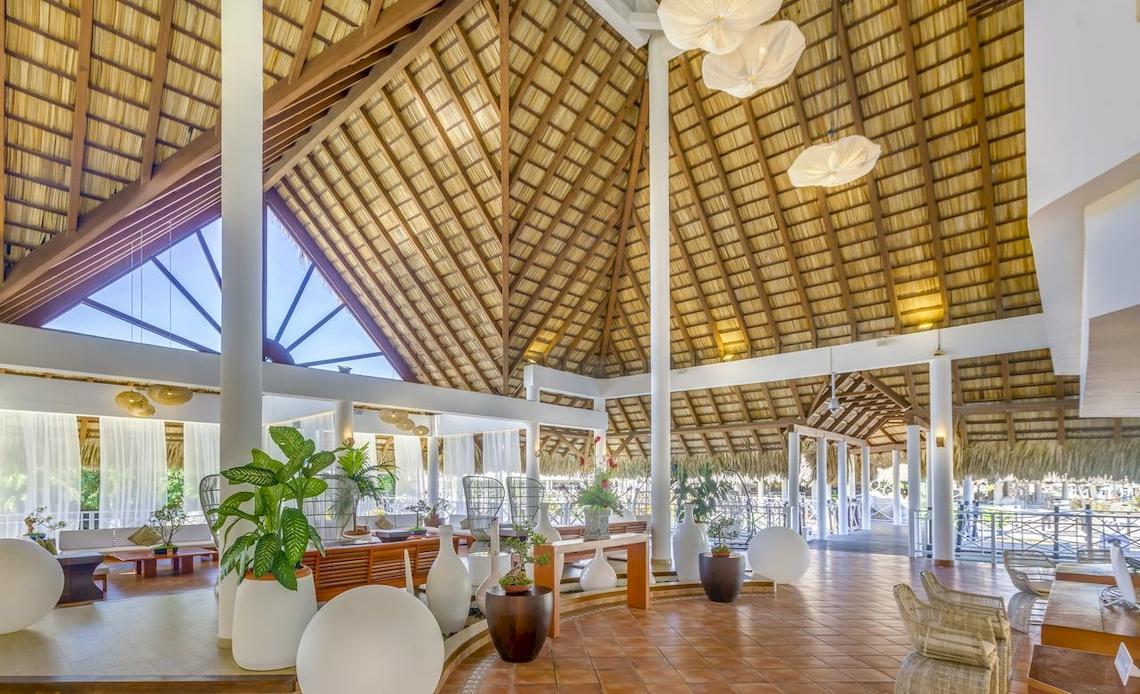 Innenbereich des Royalton Hicacos Resort & Spa mit braunen Fliesen, weißen Vasen, Pflanzen und hängenden Lampen.