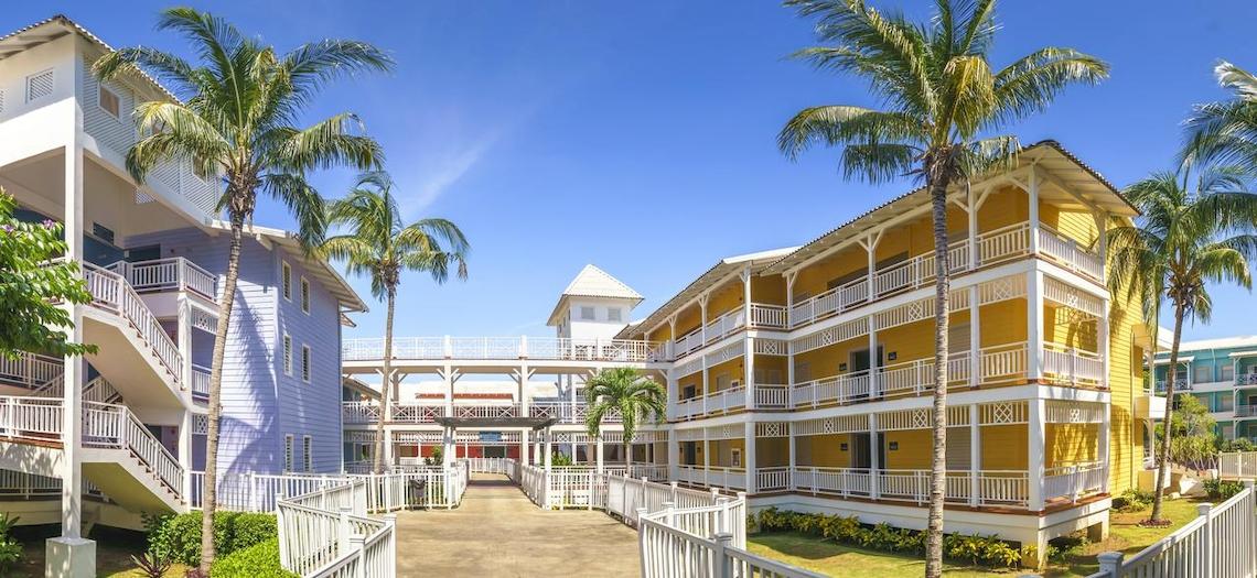 Royalton Hicacos Resort & Spa mit gelben und blauen Gebäuden, weißen Balkonen und Palmen