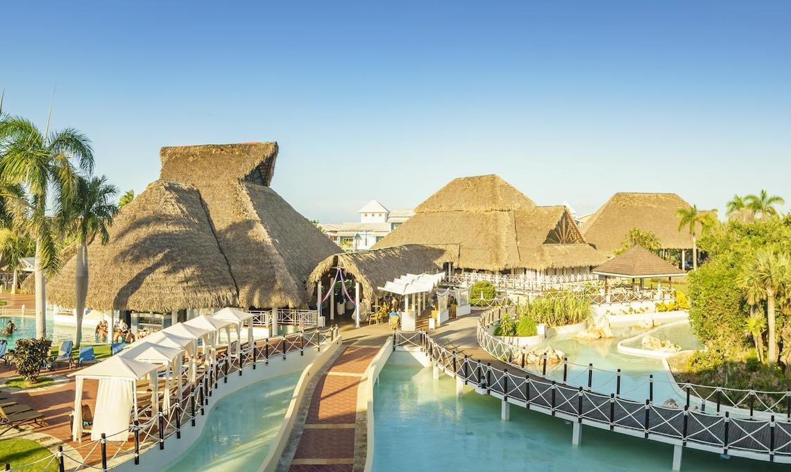 Außenansicht des Royalton Hicacos Resort & Spa mit ruhigen Swimmingpools und traditionellen Strohdächern.