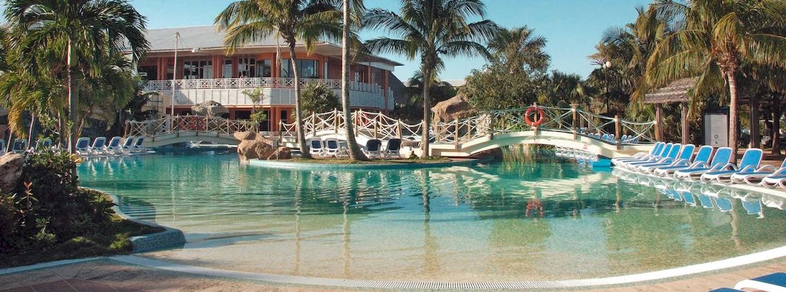 Außenpool des Royalton Hicacos Resort & Spa mit Brücke und Sonnenliegen.