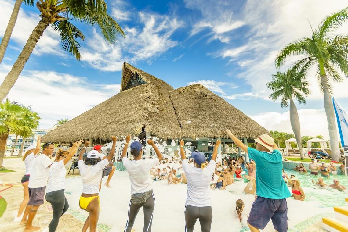 Poolparty im Royalton Hicacos Resort & Spa mit vielen Teilnehmern und Palmen im Hintergrund.