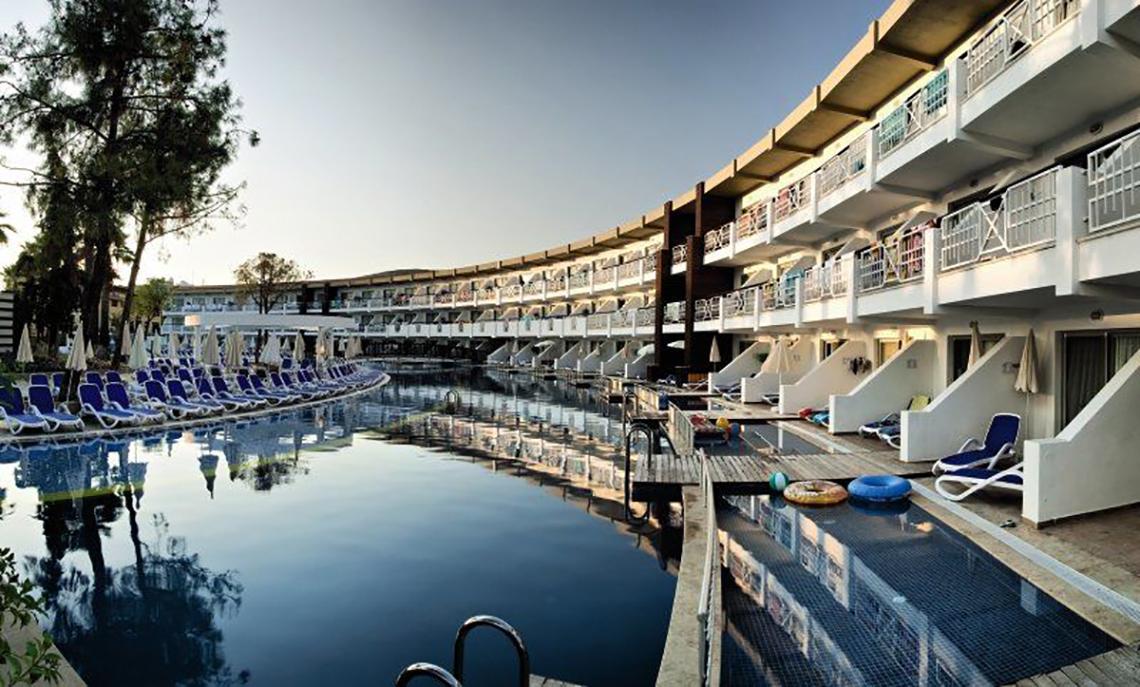 Außenbereich des Ephesia Holiday Beach Club Hotels mit Swimmingpool und Sonnenliegen.