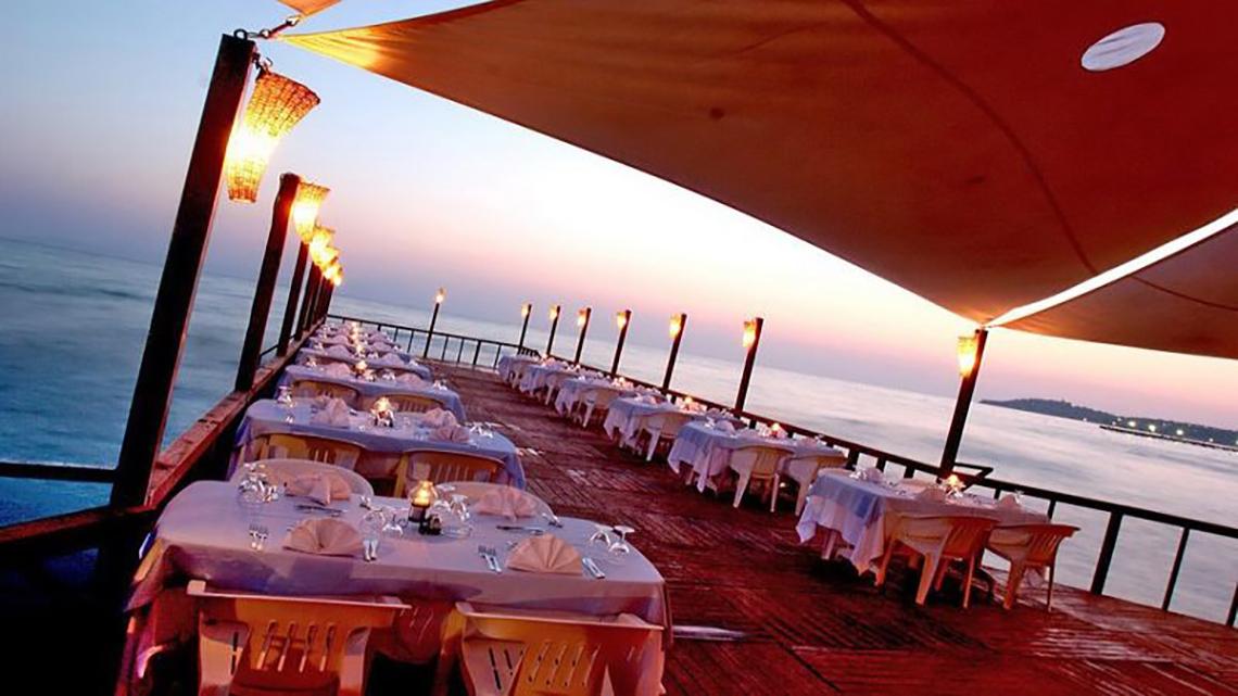Abendessen am Strand im Ephesia Holiday Beach Club mit Blick auf das Meer und gedeckten Tischen.