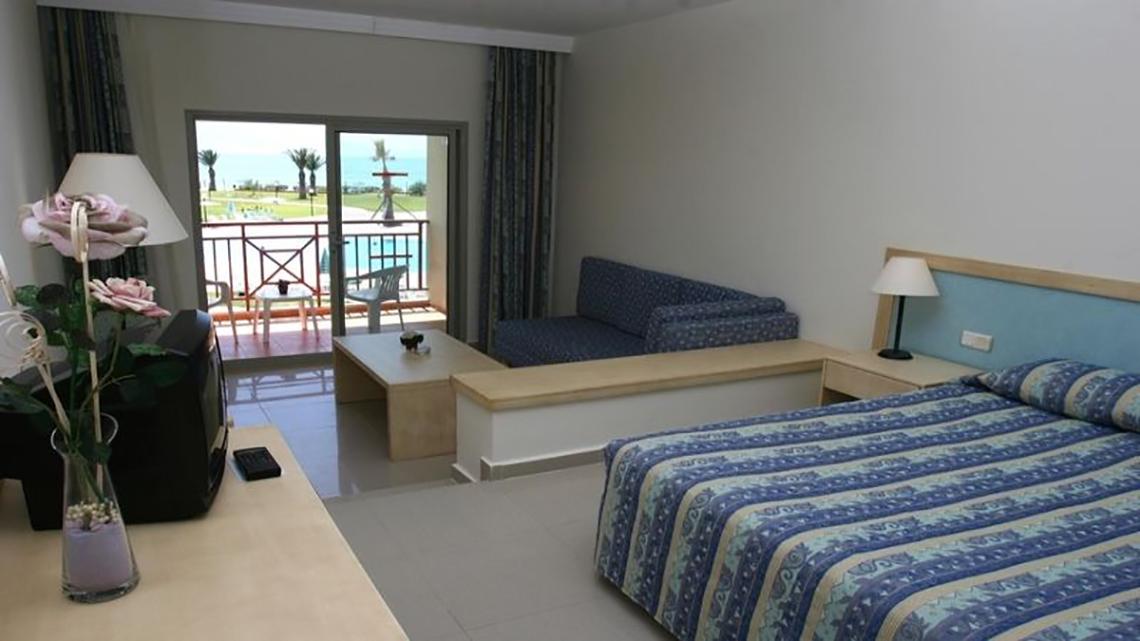 Ein Hotelzimmer im Ephesia Holiday Beach Club mit einem Bett, einer Couch, einem Tisch und einem Balkon mit Meerblick.