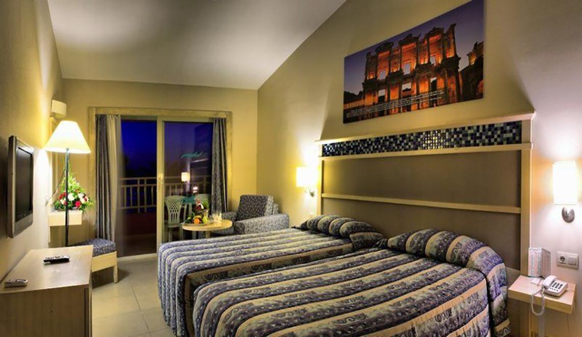 Doppelzimmer im Ephesia Holiday Beach Club mit zwei Betten, Tisch, Fernseher und Balkon.