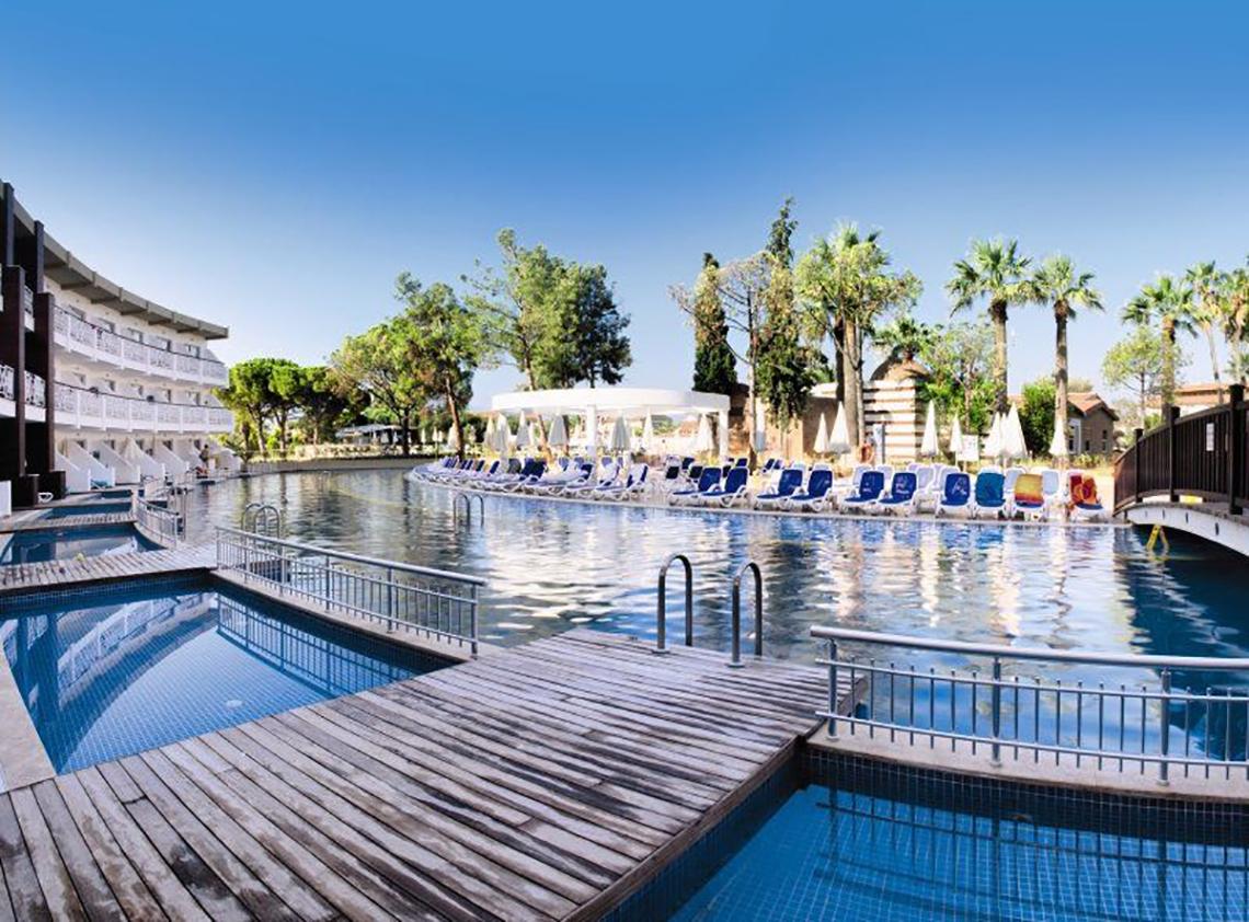 Außenpool des Ephesia Holiday Beach Club Hotels mit Holzsteg und Liegestühlen.