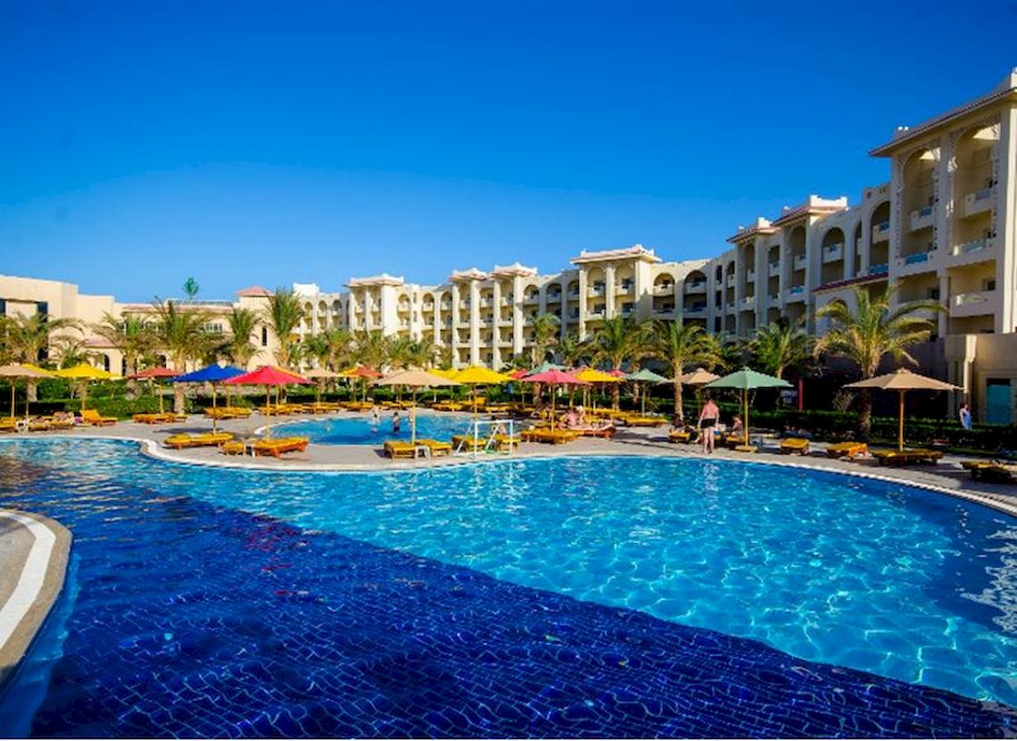 Außenpoolbereich des Serenity Alma Heights Hotels mit vielen bunten Sonnenschirmen und Liegestühlen.