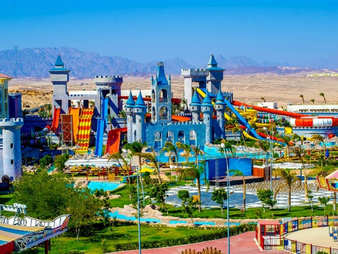 Außenansicht des Wasserparks Serenity Alma Heights mit bunten Schlössern und Rutschen.