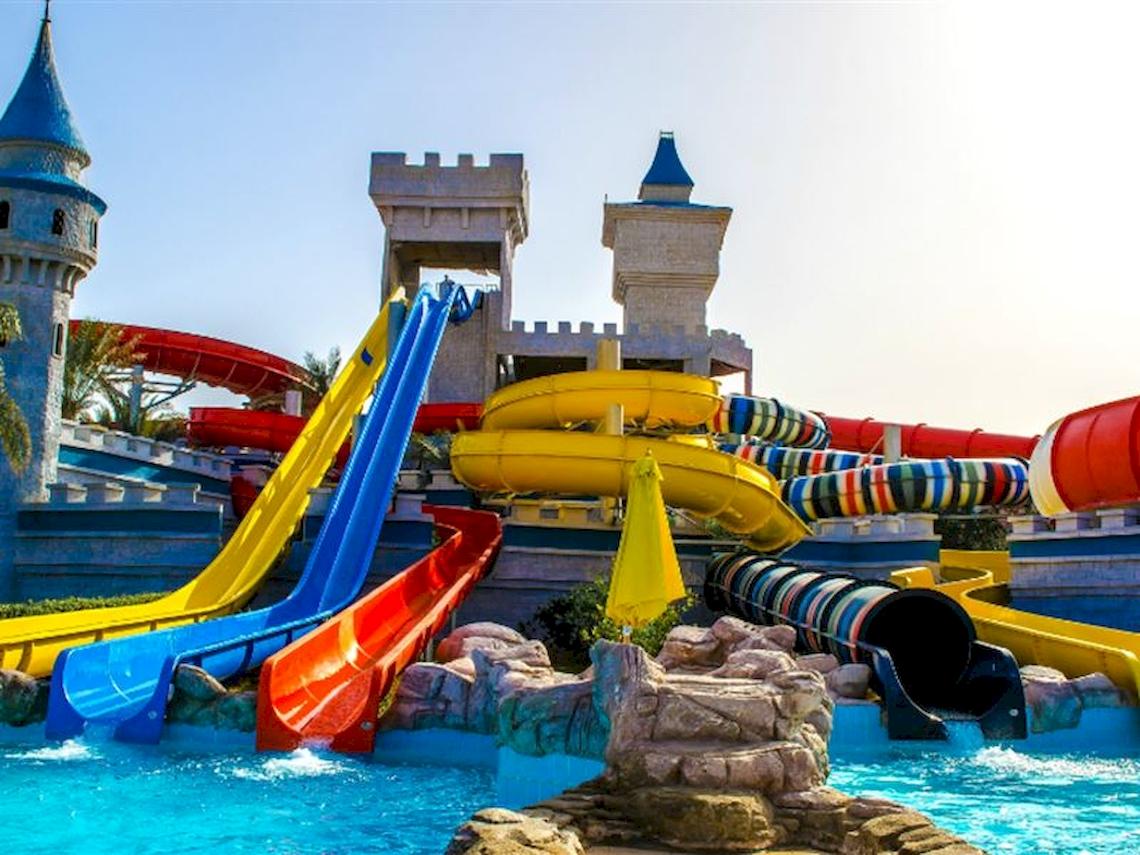 Wasserpark des Serenity Alma Heights Hotels mit bunten Rutschen und Burg im Hintergrund