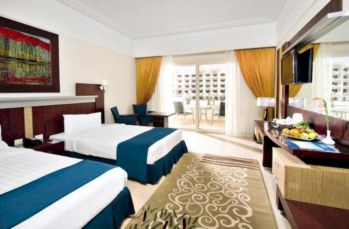Doppelbettzimmer im Serenity Alma Heights Hotel mit Blick auf Gebäude und Balkon.