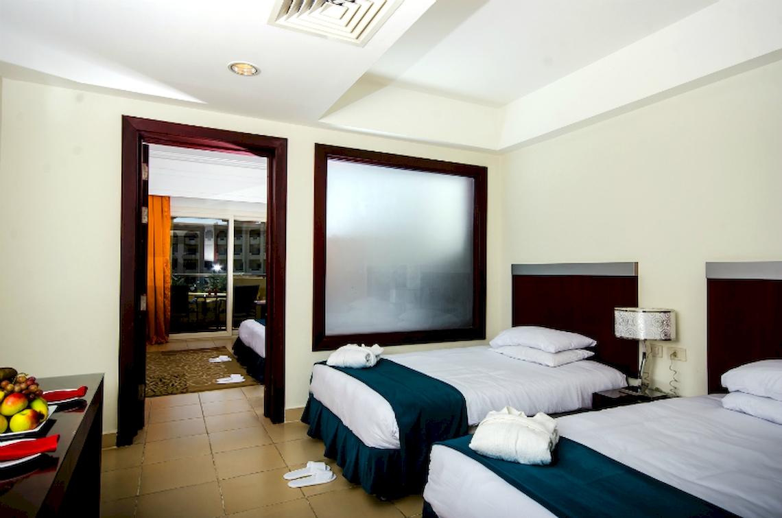 Doppelzimmer im Serenity Alma Heights Hotel mit zwei Betten, frischen Handtüchern und Früchten auf dem Tisch.