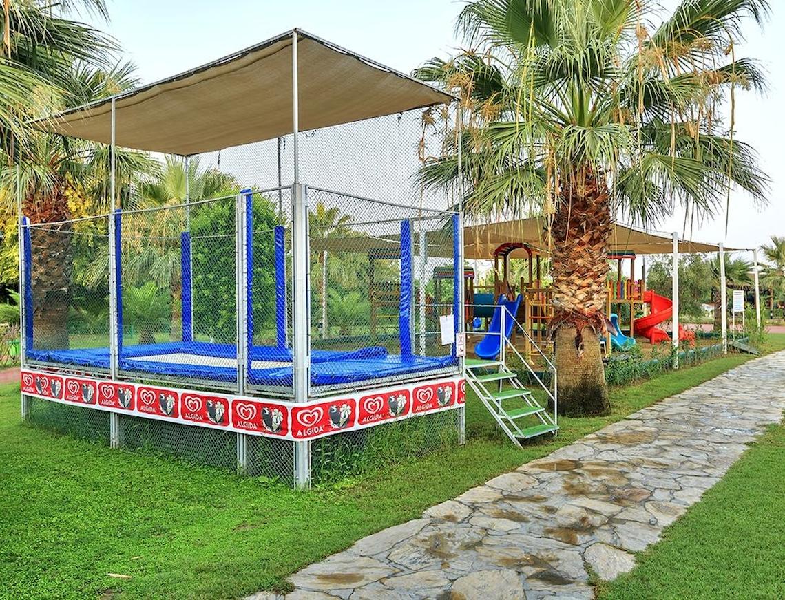 Spielplatz für Kinder im Sunis Elita Beach Resort Hotel & Spa mit Trampolin und Rutschen.