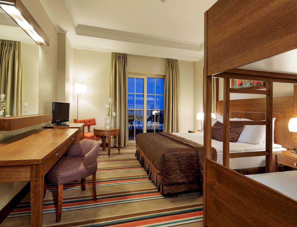 Ein Schlafzimmer im Sunis Elita Beach Resort Hotel mit einem Bett, Schreibtisch und Fenstern.