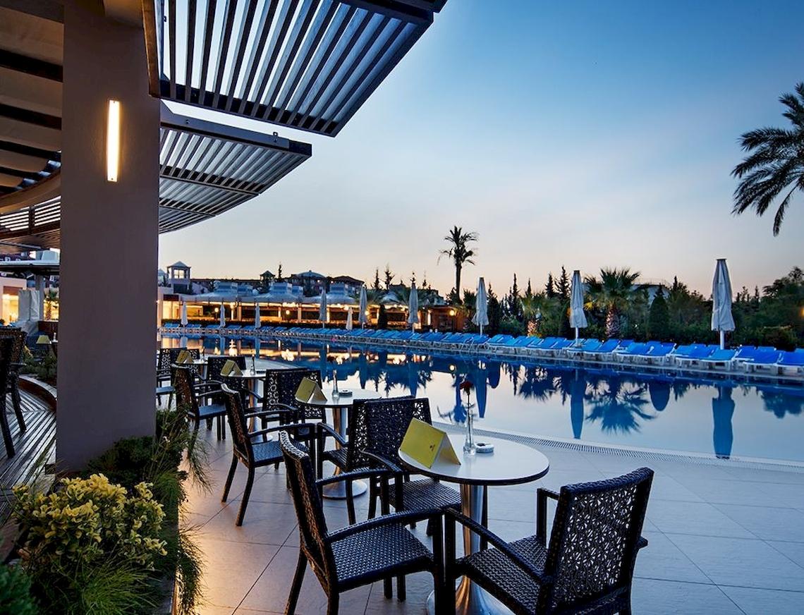 Poolbereich des Sunis Elita Beach Resort Hotel & Spa mit Tischen und Sonnenliegen