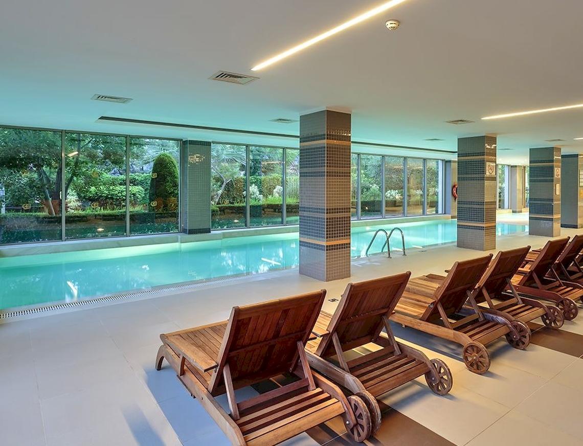 Innenpool des Sunis Elita Beach Resort Hotel & Spa mit mehreren Liegen nebeneinander