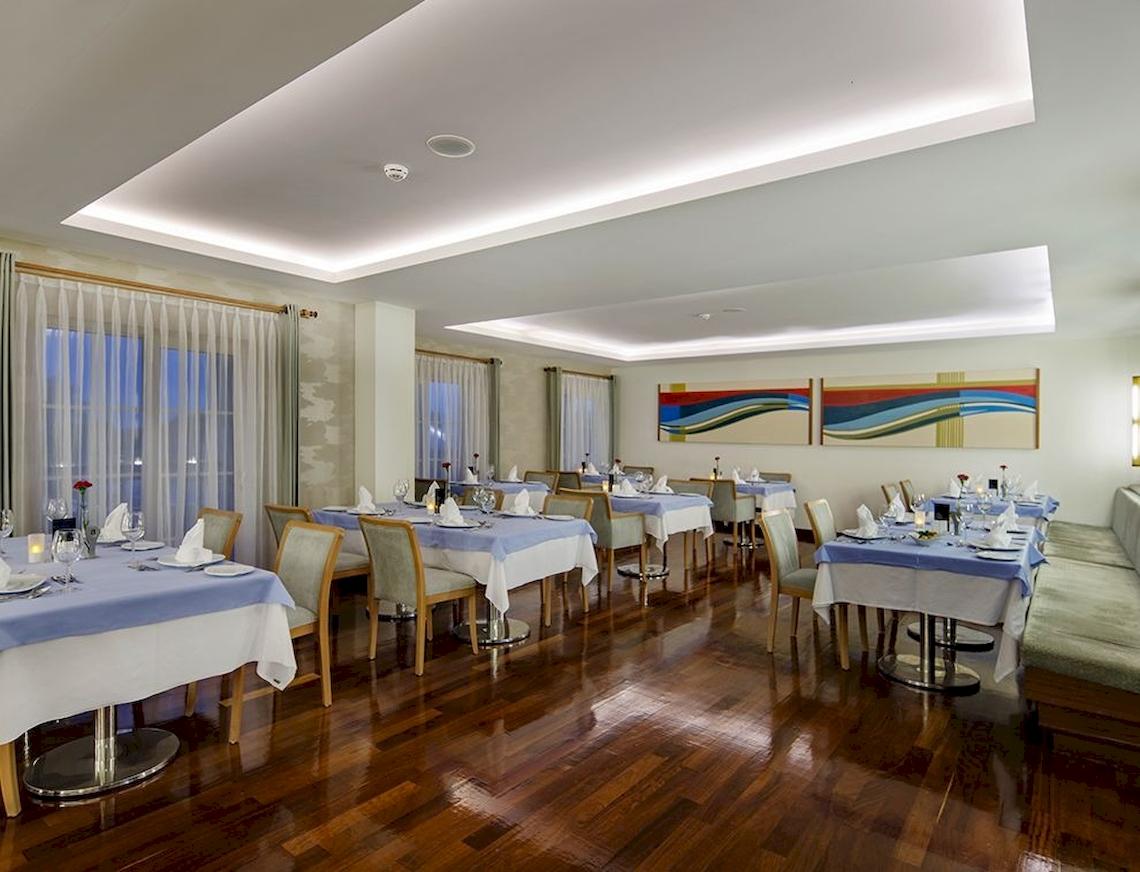 Restaurant im Sunis Elita Beach Resort Hotel mit blauen Tischen und Stühlen auf Holzboden.