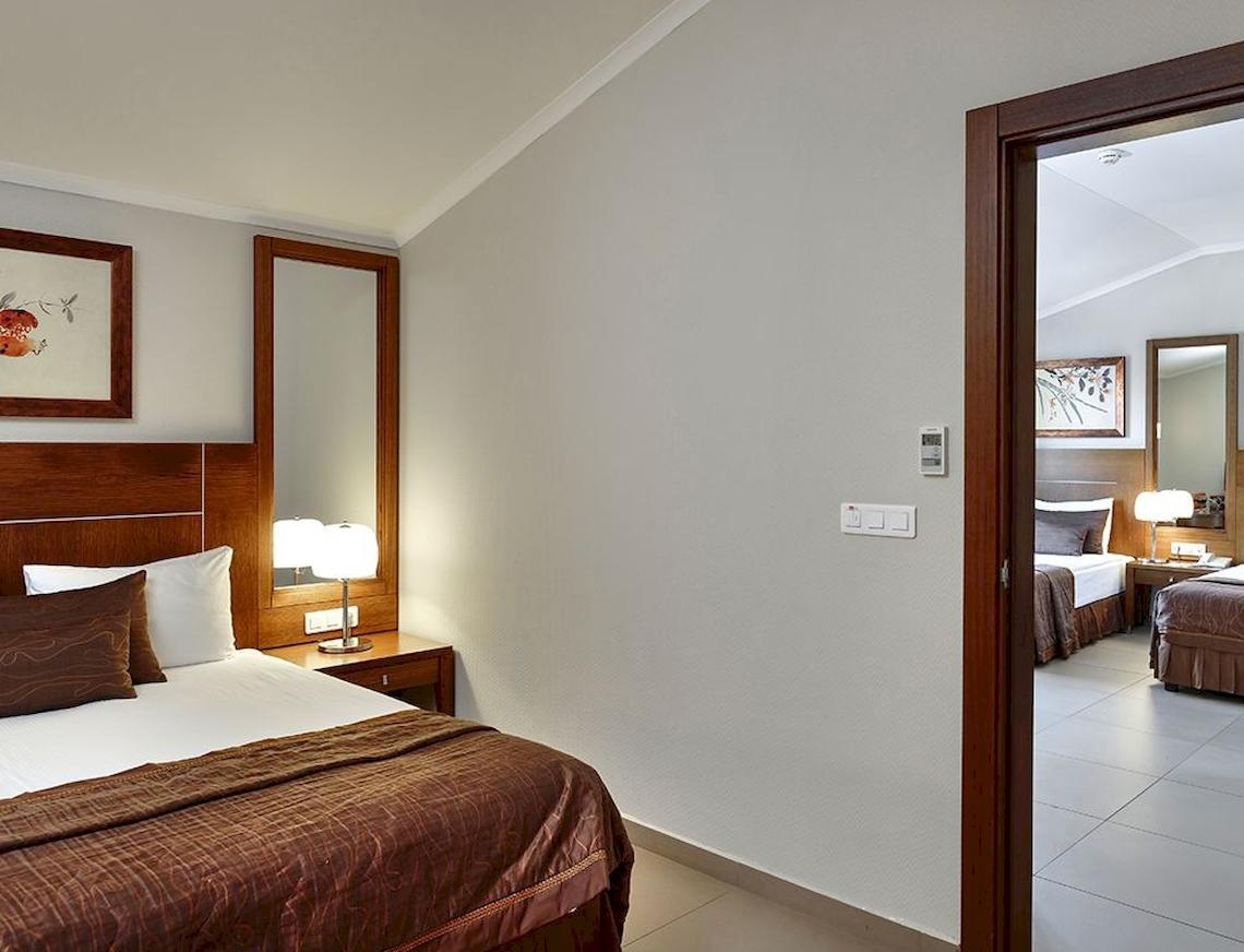 Zimmer im Sunis Elita Beach Resort Hotel & Spa mit Bett, Lampen und Spiegeln.