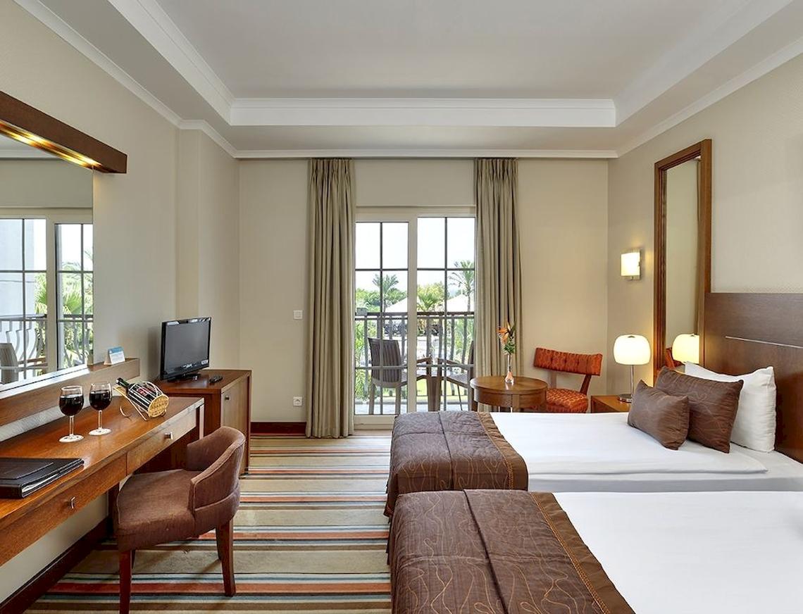 Hotelzimmer im Sunis Elita Beach Resort Hotel & Spa mit zwei Betten, Schreibtisch und Balkon.