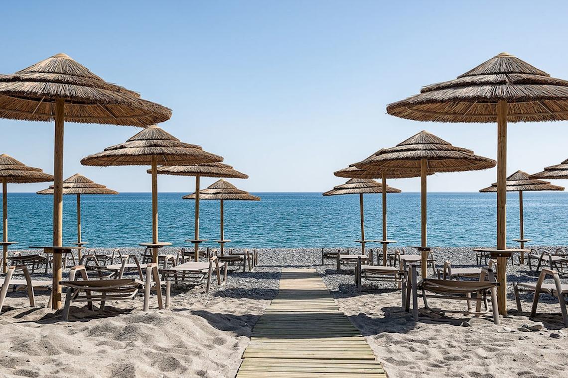 Strand des Euphoria Resorts mit vielen Sonnenschirmen und Tischen am Meer