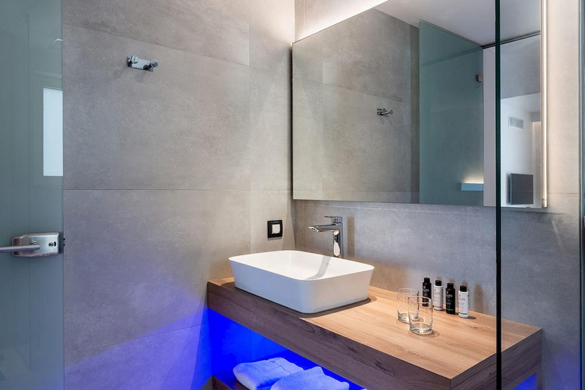 Badezimmer im Euphoria Resort mit grauen Fliesen, weißem Waschbecken und beleuchtetem Unterschrank.