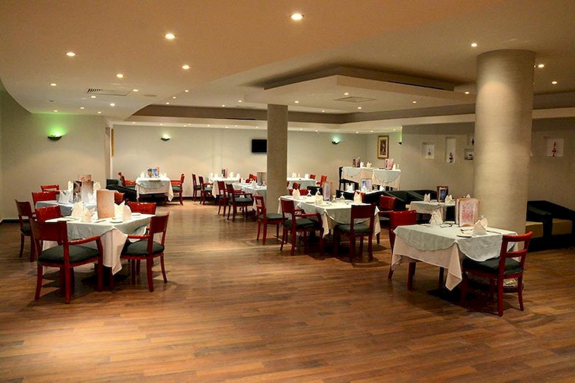 Innenansicht des Restaurants im Malikia Resort Abu Dabbab mit gedeckten Tischen und Stühlen.