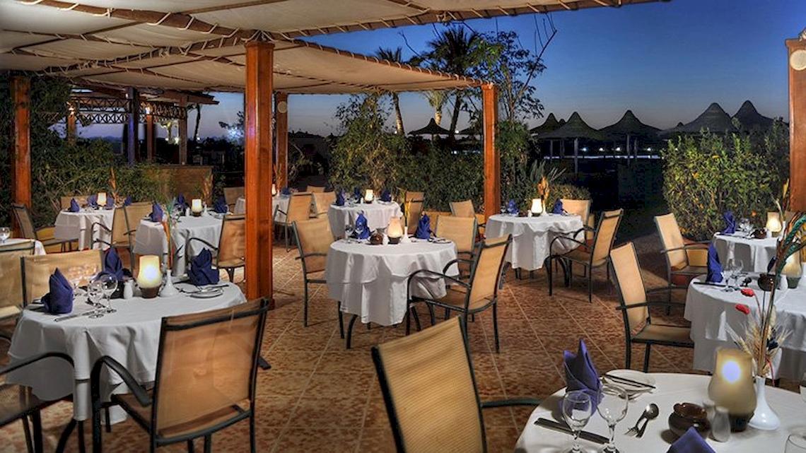 Außenbereich des Restaurants im Malikia Resort Abu Dabbab mit gedeckten Tischen und Stühlen.