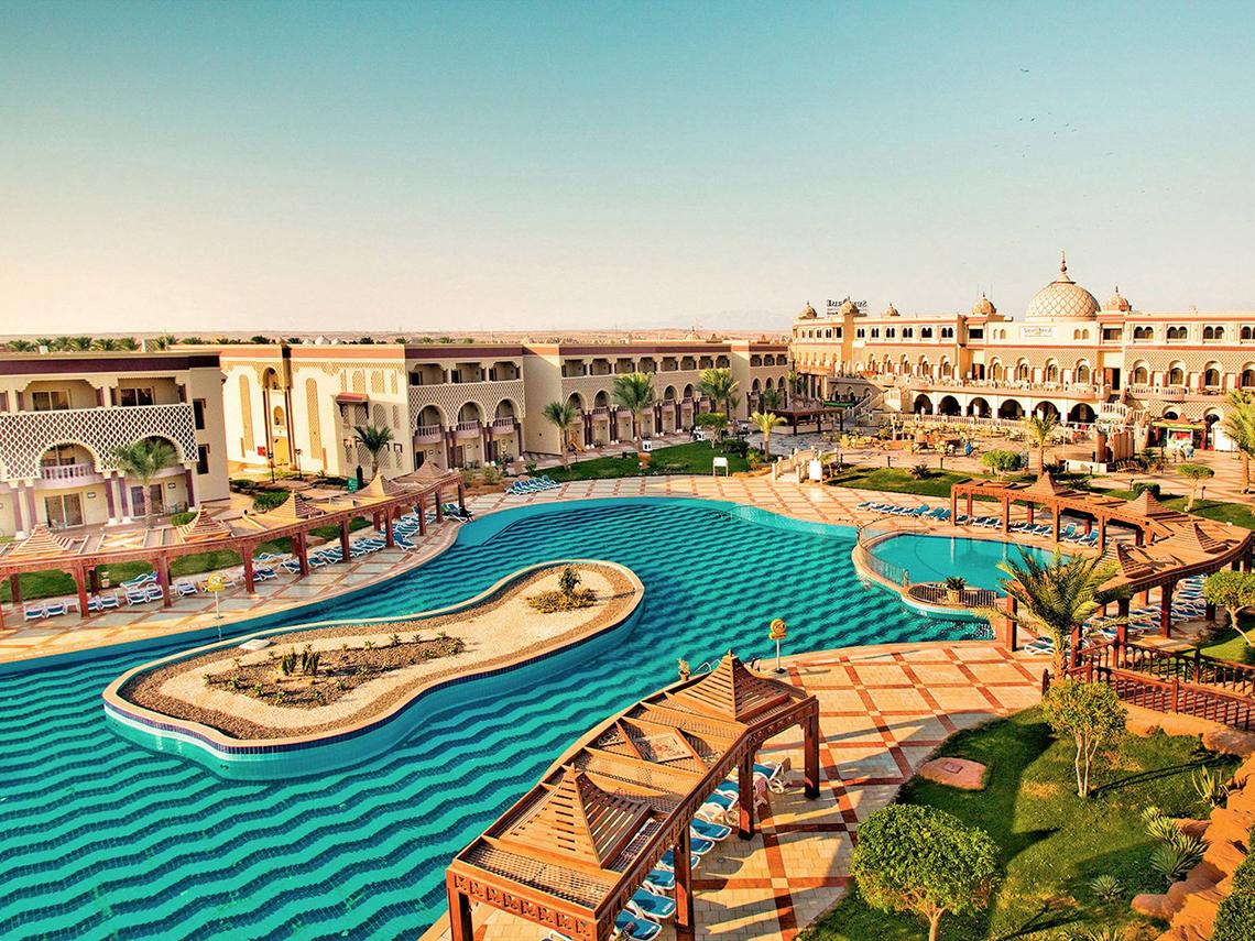 Außenansicht des Mamlouk Palace Resorts mit großen Pool und umliegenden Gebäuden.