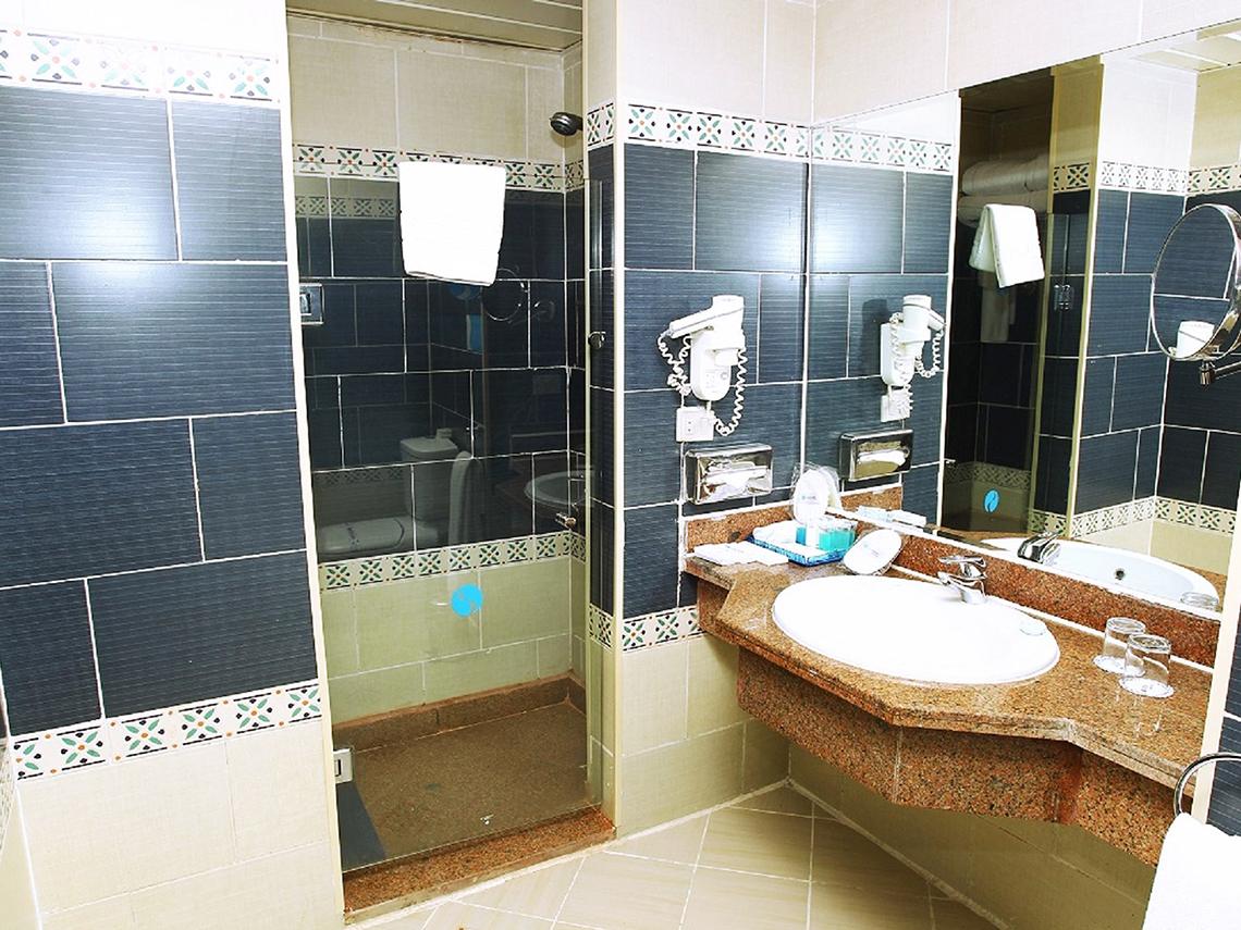 Badezimmer des Sentido Mamlouk Palace Hotels mit blauen Fliesen, Duschkabine und Waschbecken.