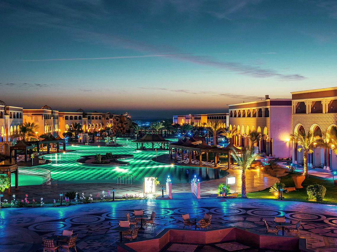 Abendliche Ansicht des Sentido Mamlouk Palace mit beleuchtetem Swimmingpool und Gebäuden