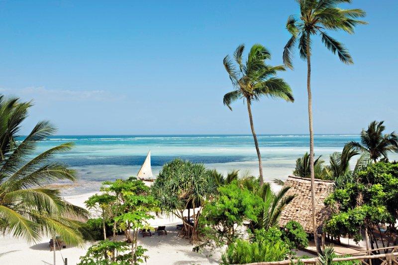 Tropischer Strand mit weißen Palmen und einer kleinen Hütte am Melia Zanzibar Hotel
