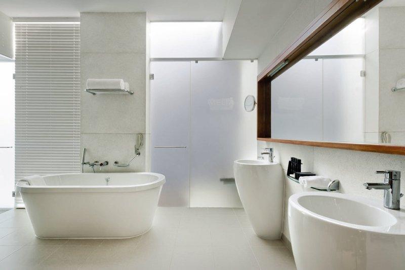 Modernes Badezimmer mit Badewanne, Waschbecken und Spiegel im Melia Zanzibar Hotel.