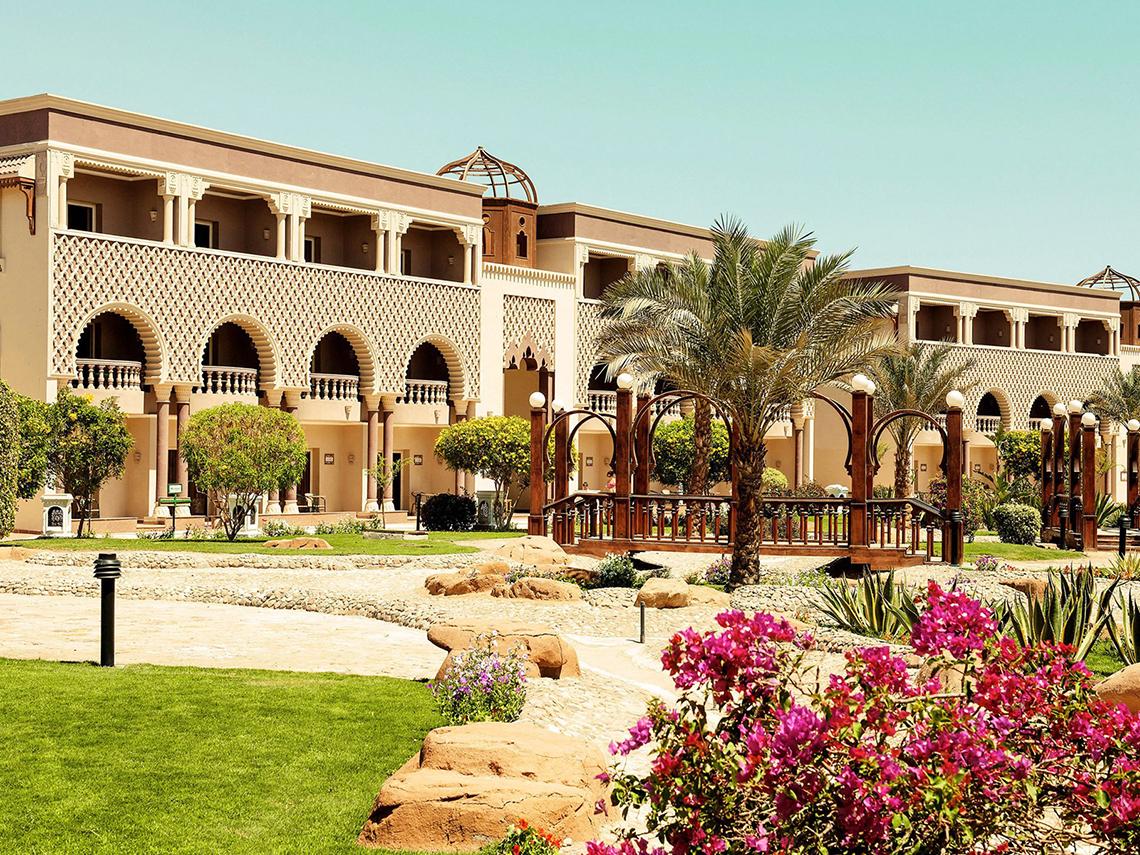 Außenansicht des Sentido Mamlouk Palace Hotels mit traditioneller Architektur, geschwungenen Bögen und gepflegtem Garten.