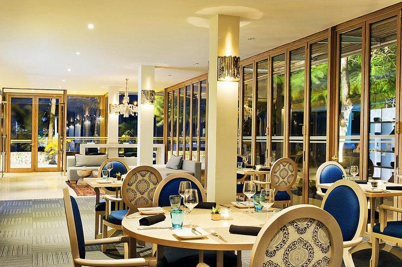 Innenraum des Restaurants im Melia Zanzibar Hotel mit blauen Stühlen und Holztischen.