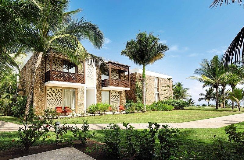 Außenansicht des Melia Zanzibar Hotels mit zwei Stockwerken, Balkonen und grüner Gartenanlage.