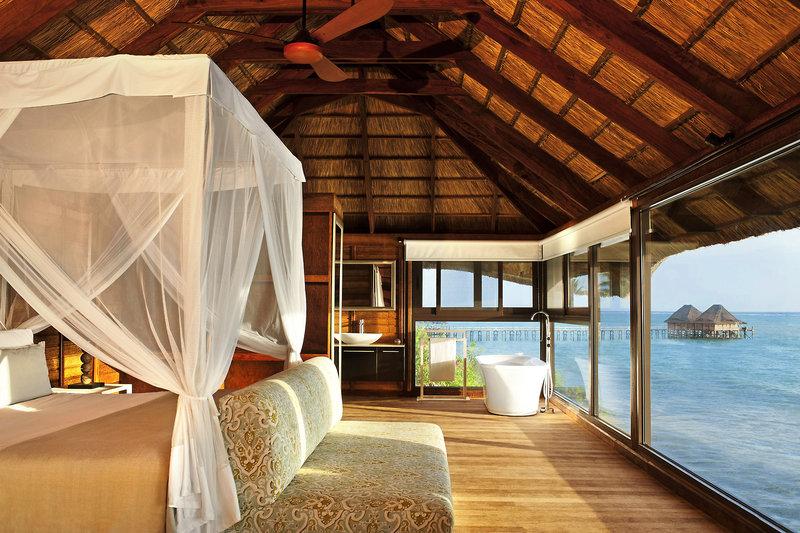 Luxuriöse Suite im Melia Zanzibar mit Meerblick, Bett mit Baldachin, Badewanne und großen Fenstern.