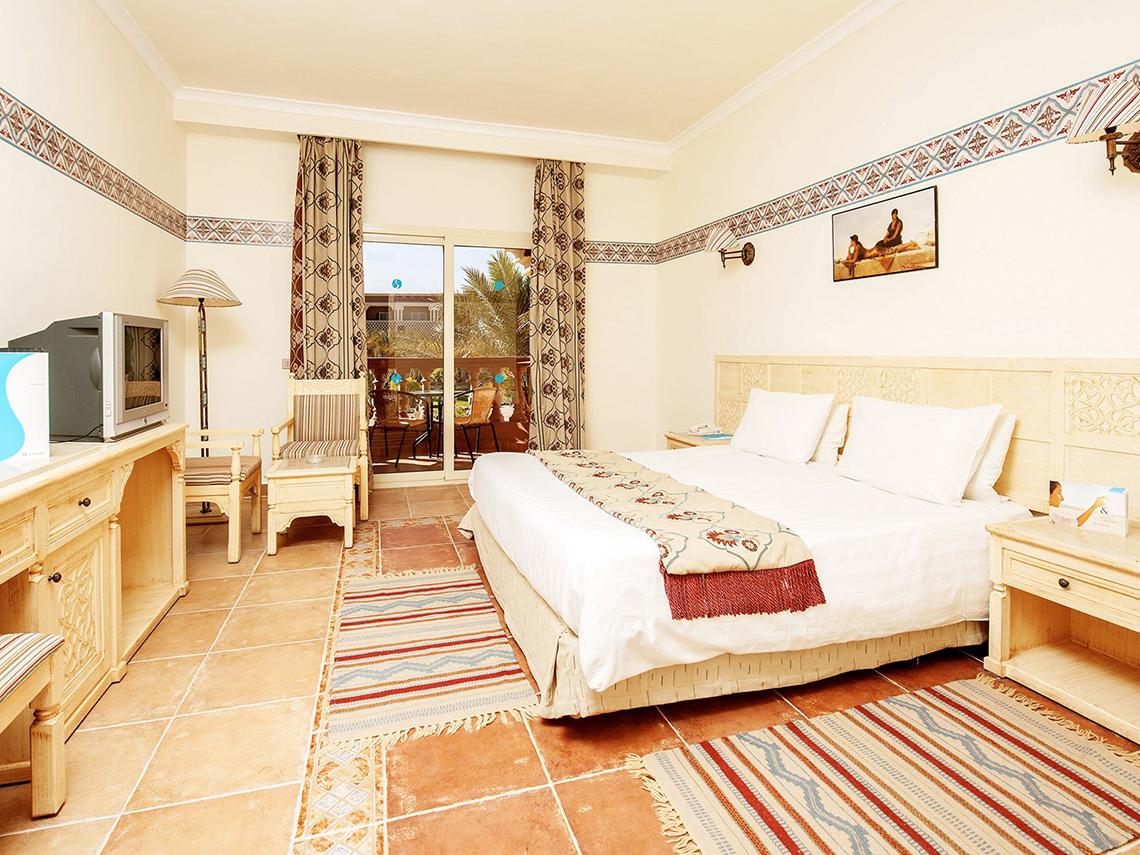 Hotelzimmer im Sentido Mamlouk Palace mit Doppelbett, Fernseher, Schreibtisch und Balkonzugang.