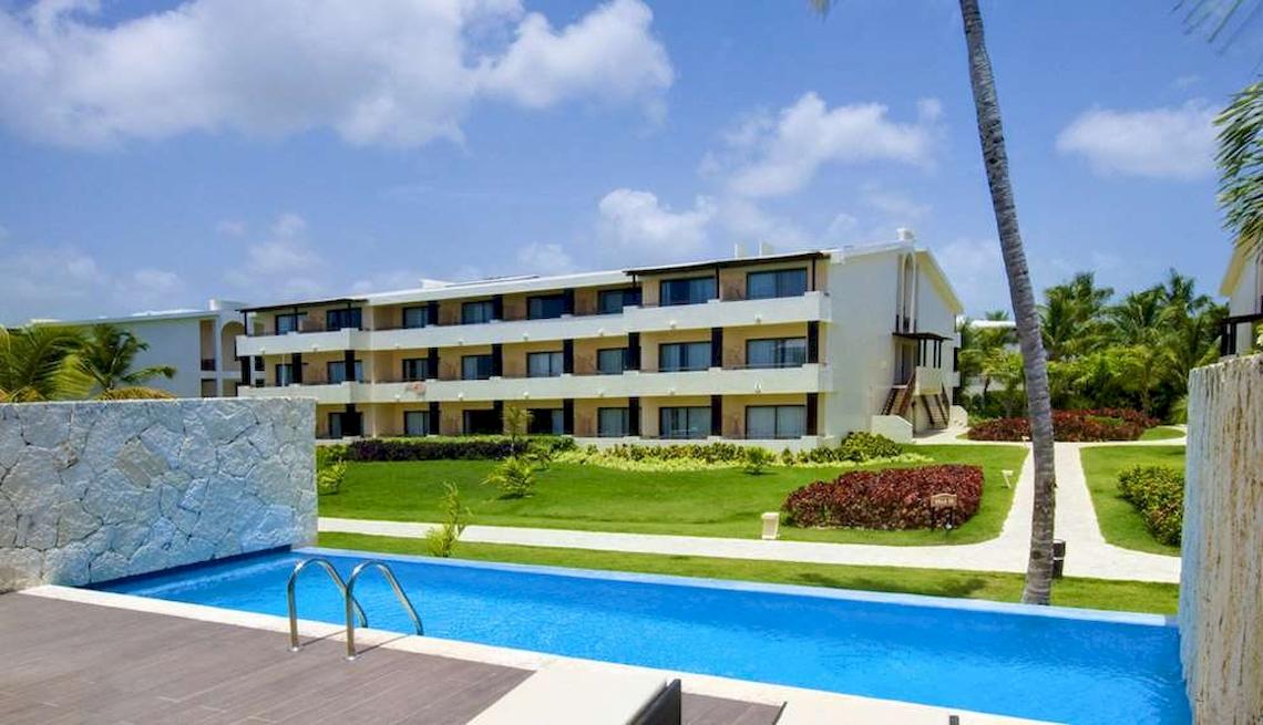 Außenansicht des Catalonia Royal Bavaro Hotels mit Swimmingpool und grüner Rasenfläche.