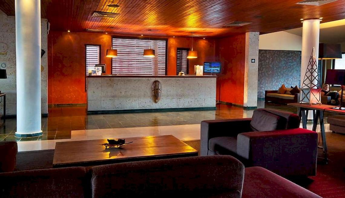 Empfangsbereich des Catalonia Royal Bavaro Hotels mit Rezeptionstresen, Sitzbereich und Fernseher.